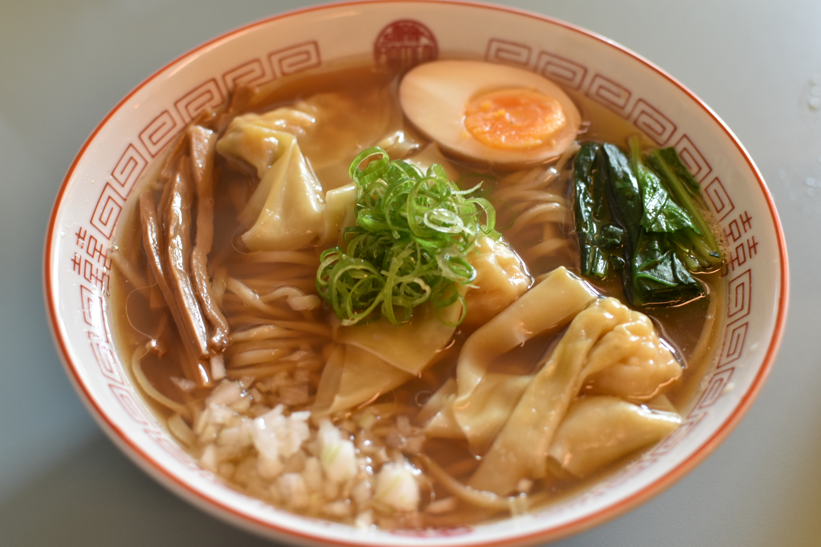 Shoyu ramen with wontons, pork and chicken chashu, ajitama egg, scallions, and chopped onions at Smaak Ramen Amsterdam, Netherlands.
