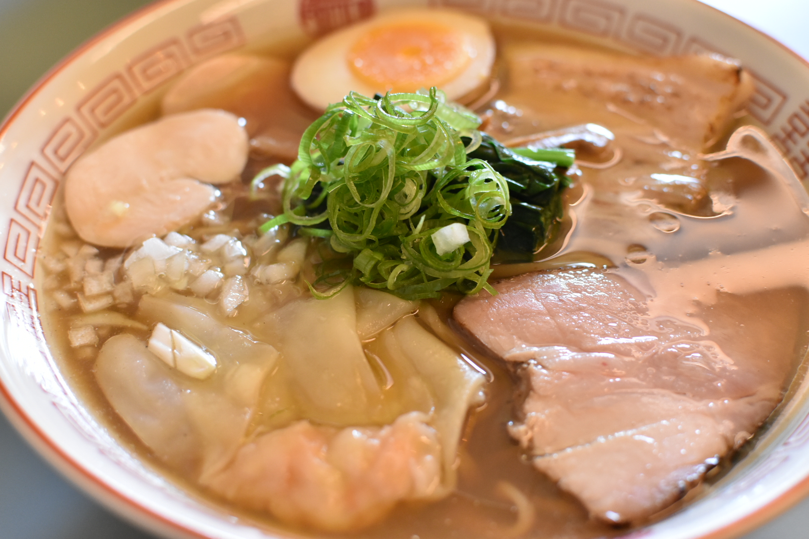 Shoyu ramen with wontons, pork and chicken chashu, ajitama egg, scallions, and chopped onions at Smaak Ramen Amsterdam, Netherlands.