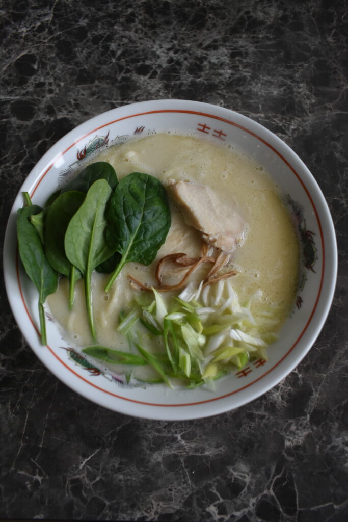 Chicken paitan ramen from Ramen Nikkou with creamy broth, thin noodles, spinach, and green onions
