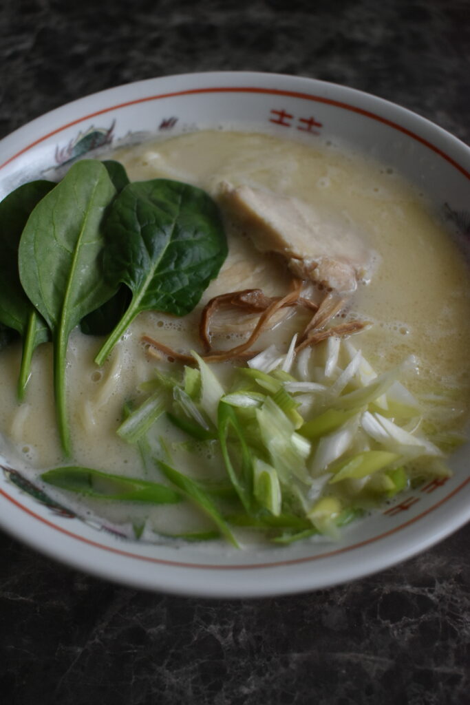 Chicken paitan ramen from Ramen Nikkou with creamy broth, thin noodles, spinach, and green onions