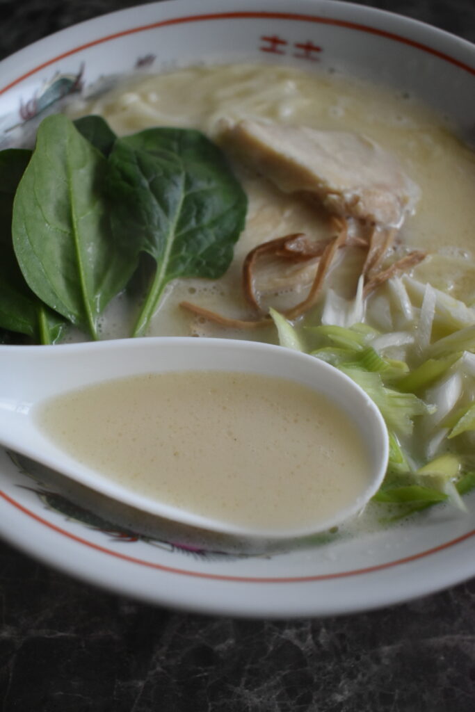 Chicken paitan ramen from Ramen Nikkou with creamy broth, thin noodles, spinach, and green onions