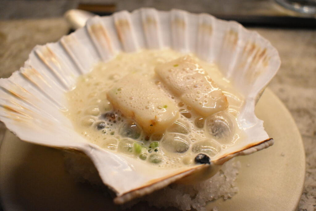 Hotate scallop served in its shell with creamy foam sauce at Fuku Ramen Amsterdam